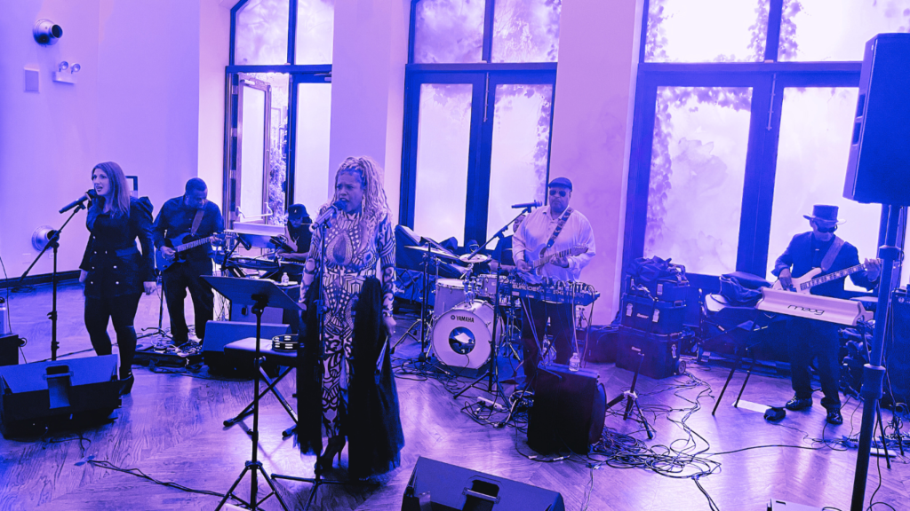 Live retro soul band performing on stage with multiple musicians and vocalists under concert lighting